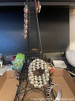 Photo showing black metal Eiffel Tower jewelry holder with multiple bracelets hanging and placed around it in a box.