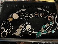 Full view of collection on black display; various rings and necklaces laid out showing styles and condition.