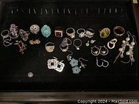 Overview of rings and earrings arranged on black background showing variety and condition