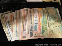 Top view of a stack of assorted used international banknotes showing different colors and partial visible denominations.