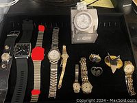 Top view of collection showing nine wristwatches and five Star Trek collectible pins in a black display tray.