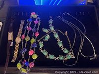 Photo showing three wristwatches and three necklaces including colorful multi-colored stone necklace, green stone necklace, and hematite-like bead necklace