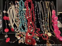 Close view of vintage fashion jewelry highlighting coral, agate, faux pearl, lava rock beads, and gold chains with pendants.