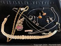 Full group showing all jewelry pieces in black display tray including necklaces, earrings, ring, cufflinks, pendants, and gold plated chain.