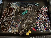 Tray of assorted fashion necklaces and jewelry items in various bead and metal designs