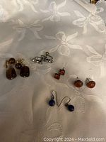 Overview of all 5 pairs of earrings on fabric background showing color and style variety