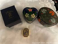 Four vintage trinket and pill boxes displayed on a white floral fabric background, includes original Adeline Collection box