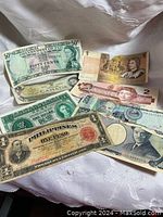 Photo showing various international banknotes including Canadian $2 Devils Face, Philippine Peso, Fiji 50 cents, and more.