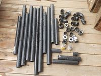 Multiple lengths of black ABS pipe along with various pipe fittings including elbows and couplings laid out on wooden floor.