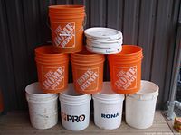 Stacked buckets showing five orange Home Depot buckets and three white buckets with various brand logos.