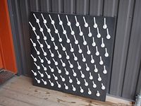 Front view of the black pegboard with white plastic pegs for drying bottles and jars, showing arrangement and peg details.