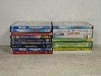 Photo of stacked DVDs showing titles like Ice Age, Christmas Sing-Alongs, Alice in Wonderland, Happy Feet, Toy Story, Ratatouille, Cars and others stacked vertically.