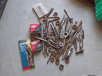 Photo showing collection of threading taps, dies, and holders with two small branded boxes containing threading tools.