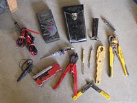 Photo showing an assortment of electricians and technicians tools including a digital multimeter, voltage tester, wire strippers, cutters, flashlight, pouch, and screwdrivers.