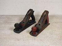 Front angled view showing two vintage metal wood block planes with wooden handles and knobs, one black and one rusted.