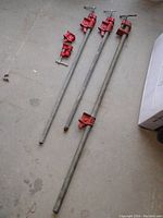 Overview of three metal pipes with red cast iron clamp heads; varying pipe lengths approximately 32, 36, and 48 inches long. Shows overall set for woodworking pipe clamps.