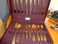 Overview photo of the boxed set showing knives in the back and other flatware in the front slots within the burgundy-lined box.