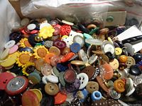 Box filled with many assorted buttons of different colors, materials and sizes.