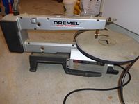 Side view of Dremel 16-inch 2-speed scroll saw showing metal frame, adjustable arm and round work table.