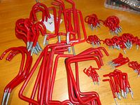 Large and small red coated hooks and supports arranged on table