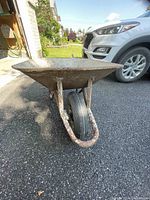 Front view of the used wheelbarrow showing rust and wear on the metal body and frame.