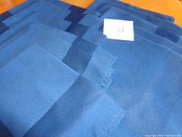 Eleven navy blue cloth napkins stacked, showing color and edges with stitching detail