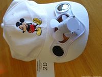 White baseball cap embroidered with Mickey Mouse figure and attached solar-powered fan on the bill.
