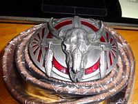 Top view of the rolled brown full grain leather belt with metal buckle showing bull skull and red accents