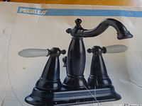 Boxed kitchen faucet showing the Peerless brand and faucet with two white handles mounted on a base plate.