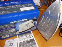 Iron and its soleplate with steam vents, positioned next to original box displaying brand and product information.