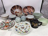 Full collection of various Asian styled dishes and bowls including two large decorative bowls, teapots, decorative plates, and multiple small bowls with floral and geometric designs.