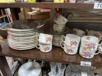 Photo of stacked plates and cups with floral patterns in varied colors.