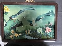 Front view of the reverse glass painting showing birds, flowers, and natural scenery in a wooden frame with brass hanger.
