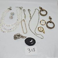 Photo shows full assortment of vintage jewelry including rhinestone necklace, earrings, bracelets, brooches, ring, and watch.items arranged around card labeled 318