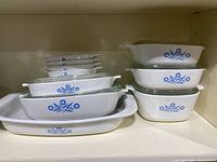 Overview of left-side stack: large open baker, two nested casseroles with lids, four small individual dishes