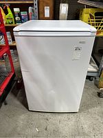 Front view of the white Kenmore mini fridge showing some dents on the door.