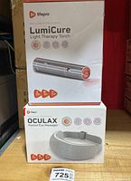 Boxes of Lifepro LumiCure Light Therapy Torch and Oculax Heated Eye Massager stacked showing product branding and usage icons.