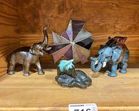 Shelf display showing the two metal elephants, the stained glass sun catcher, and the drip glaze horse sculpture.