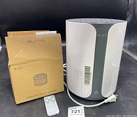 Miko Air Enhancer device with power cord, new filter box, and remote control on table.