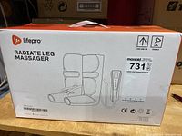 Front view of the product box showing brand Lifepro, product name Radiate Leg Massager, illustration of leg sleeves and controller, with shipping label.