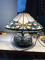 Front view of the small stained glass lamp showing the colorful floral and swirl design on shade and base