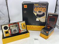 Overview of the Kodak Brownie Starmite II camera in original box, Kodak Carousel Projector 4200 original box, Vivitar slide viewer box, and two Kodak projection extra C lens boxes.