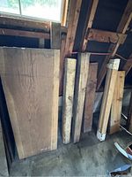 Front view of assorted boards leaning against stud wall under window, showing large oak panel and narrower blocks