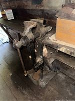 Blacksmith jack mounted on wooden workbench, showing overall shape and condition.