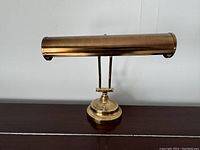 Front view of brass piano lamp showing cylindrical shade and round base.