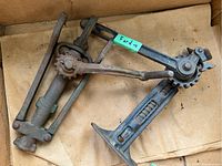 Full view of the metal jack showing lever, base, and gear mechanism on a brown paper background.