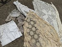 Photo showing assorted linens and doilies in white and cream colors with crochet and embroidery details.