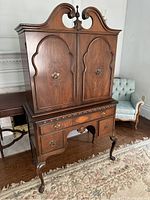 Full view of the mahogany liquor cabinet hutch in a room with hardwood floors and a patterned rug, showing upper and lower cabinet sections and cabriole legs.