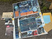 Full view of all items included in the lot showing newspaper, booklet, Life magazine, posters, maps, and an envelope with related documentation.
