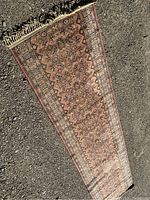 Full view of runner rug laid on asphalt showing length and pattern detail.